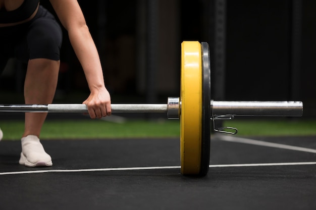 Person performing barbell squat with proper form and blood pressure monitor nearby