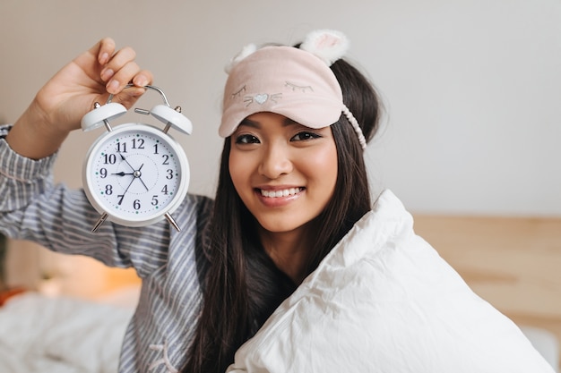 Person sleeping with alarm clock showing consistent wake-up time