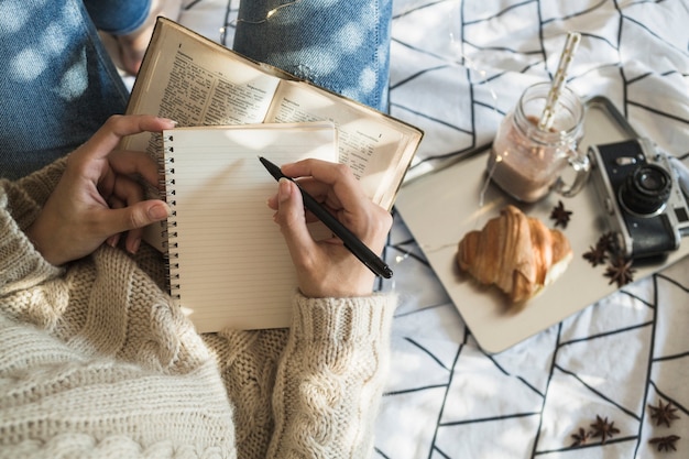 Someone writing in a journal with a warm cup of tea