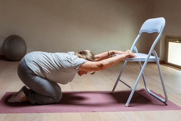 Woman sitting on a chair with hands on belly, focusing on spine alignment