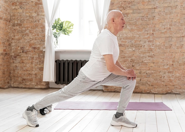 Senior man using a strap to stretch his hamstring while seated